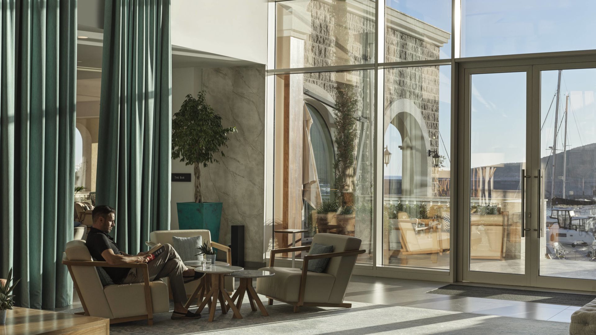 A Person Sitting In A Chair In A Room With Large Windows
