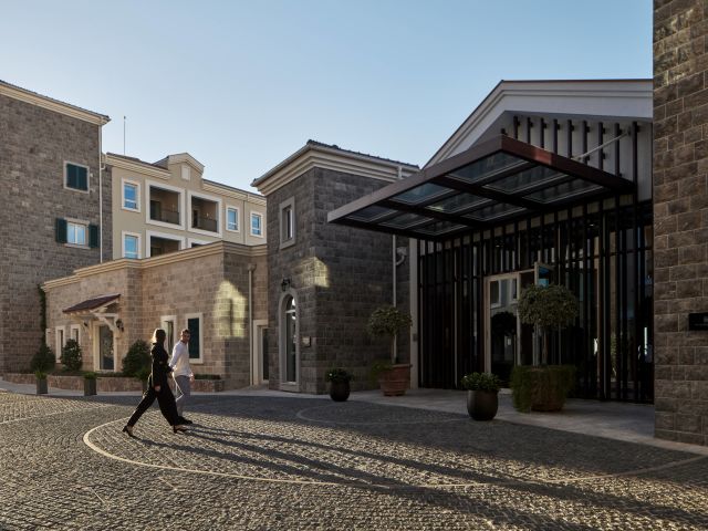 A Person Walking In A Courtyard Between Buildings